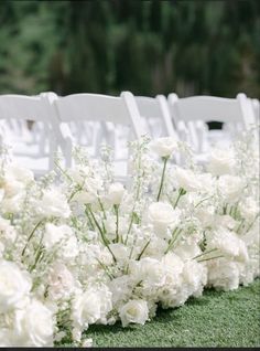 rows of white chairs with flowers on the grass in front of them at a wedding