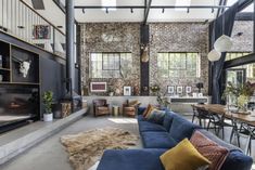 a living room filled with furniture and a fire place next to a brick wall covered in windows