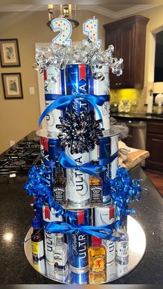 a birthday cake made out of cans with blue ribbons and decorations on top, sitting on a kitchen counter