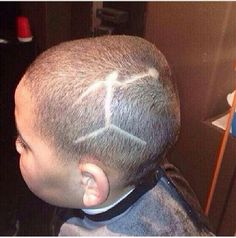 a man with a shaved head has scissors in his hair and is looking at the mirror