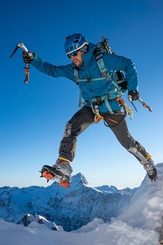 a man on skis jumping off the side of a snow covered mountain with mountains in the background