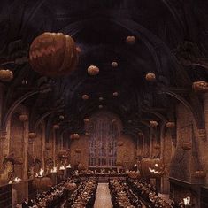 a large dining hall filled with lots of tables covered in pumpkins and hanging from the ceiling