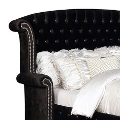 an upholstered bed with white pillows and black headboard