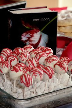 there are many candy lollipops in the bowl on the table next to books