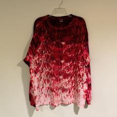 a red and white tie dye shirt hanging on a wall next to a hanger