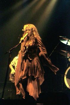 a woman standing on stage with a microphone in her hand