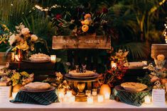 a table topped with lots of plates covered in flowers and candles next to a wooden sign