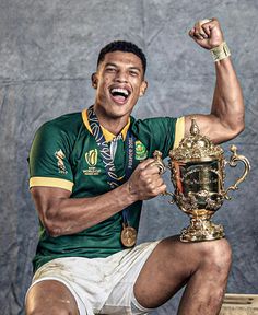 a man sitting on top of a wooden bench holding a trophy and raising his fist