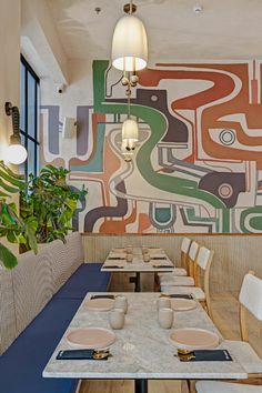 a dining room with tables and chairs in front of a colorful mural on the wall