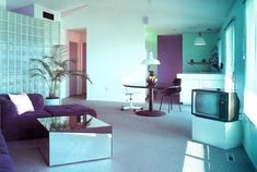 a living room filled with furniture and a flat screen tv mounted to the wall in front of a window