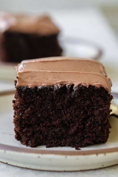 a piece of chocolate cake on a plate with a fork in front of the slice