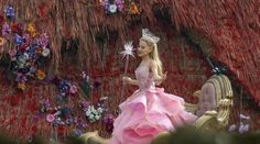 a barbie doll dressed in a pink dress sitting on a gold bench with flowers around her