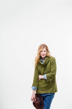 a woman in a green sweater and hat posing for the camera with her hands on her hips