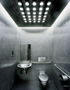 a public restroom with stainless steel walls and flooring is shown in black and white