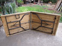 an open wooden box sitting on top of a cement floor next to a garden area