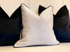 two black and white pillows sitting on top of a bed next to each other in front of a white headboard