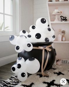 black and white balloons are sitting in a pot on the floor next to a shelf