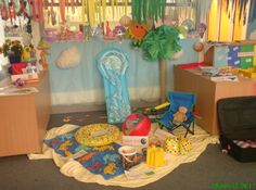 a room filled with lots of toys and decorations on the floor, including a blue chair