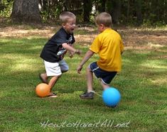 two young boys playing with balls in the grass