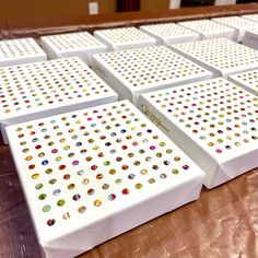 several white boxes with multicolored dots are lined up on a table in front of each other