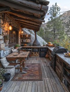 an outdoor kitchen with wood flooring next to a stone wall and wooden table on the porch