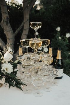 a table topped with lots of wine glasses next to a vase filled with white flowers