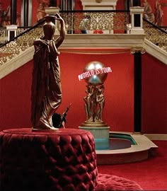 there is a statue in the center of this room with red walls and carpeted flooring