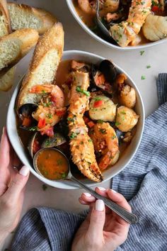 two bowls filled with seafood and bread on top of a table