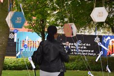 a woman standing in front of a tree with several signs hanging from it's sides