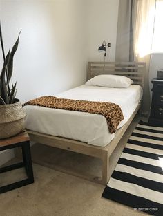 a bed with a leopard print blanket on top of it next to a potted plant