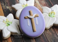 decorated cookies with white and purple icing on wooden table next to crucifix