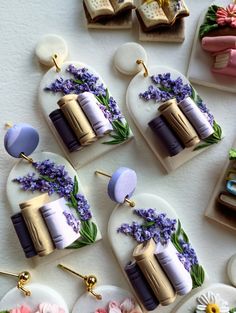 several different types of earrings on display with flowers and books in the backround