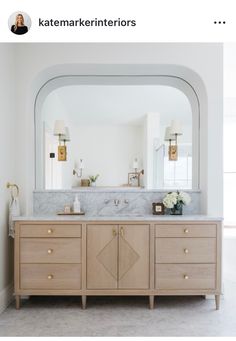 a bathroom vanity with two sinks and large mirror above it, along with an arched doorway leading to another room