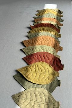 a row of different colored leaves sitting on top of a white table covered in fabric