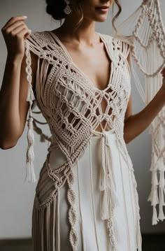 a woman in a white dress holding up some tassels on her neck and shoulders