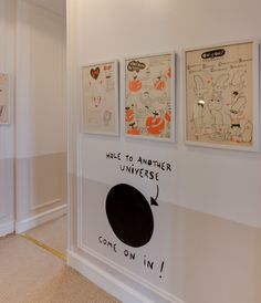 three posters are hanging on the wall in front of a white room with beige carpet