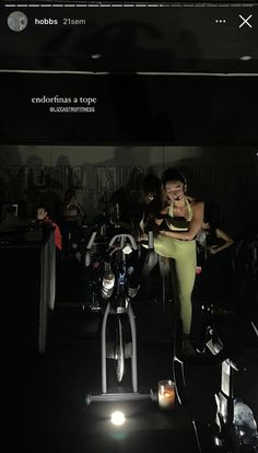 a woman standing next to a bike in a dark room