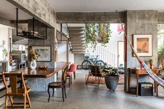 a living room filled with lots of furniture next to a stair case covered in plants