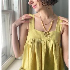 a woman standing in front of a window wearing a necklace