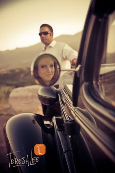 a man and woman are reflected in the side mirror of a car