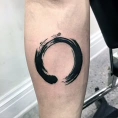 a black ink circle tattoo on the leg