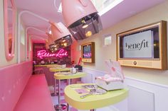 the interior of a diner with pink lighting and neon signs on the wall above the tables