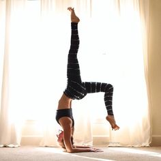 a woman doing a handstand in front of a window