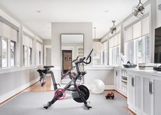 an exercise room with stationary bikes in the foreground and large windows to the side