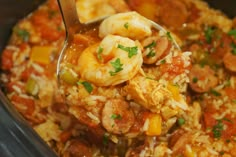 a spoon full of shrimp and rice in a crock pot with garnish