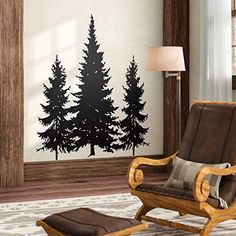 a living room with a chair and wall decal in the shape of pine trees