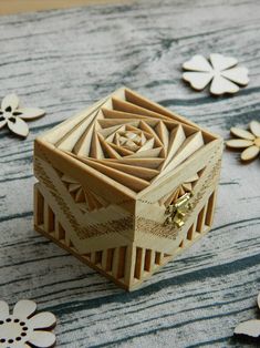 a wooden box sitting on top of a table next to some flowers and leaves in the background