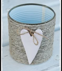 a white heart hanging from a rope wrapped candle holder