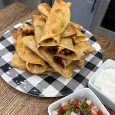 some food is on a black and white checkerboard plate next to a bowl of sour cream