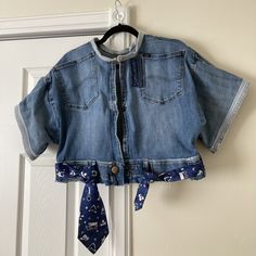 a blue jean jacket hanging on a door with a tie attached to it's collar